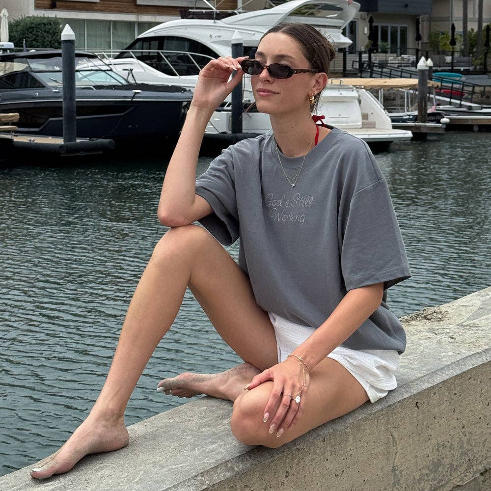 Woman sitting by a waterfront with boats in the background
