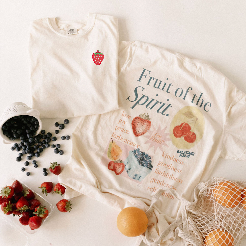 White t-shirt with fruit design and text, surrounded by fruits on a white background