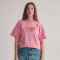 Person wearing a pink t-shirt with 'Jesus loves you' text on a plain background