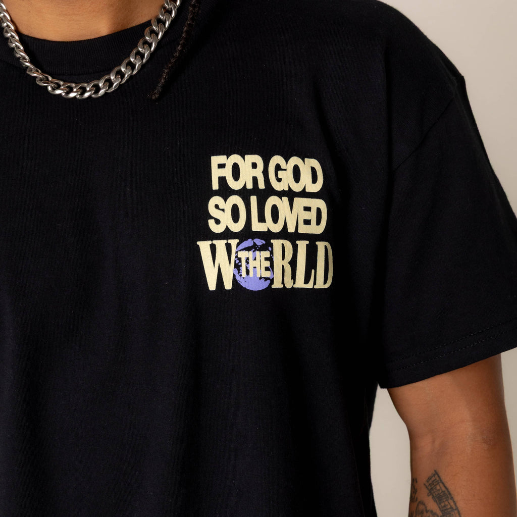 Black t-shirt with 'For God So Loved The World' text worn by a person.