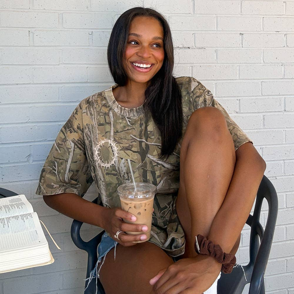 Woman sitting on a chair holding a drink with a white brick wall background